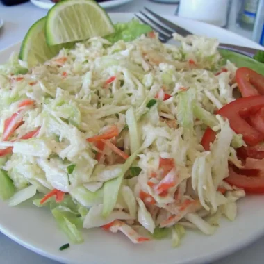 Golden Corral seafood salad with shredded cabbage, imitation crab, carrots, and creamy dressing served with lime and tomato slices.