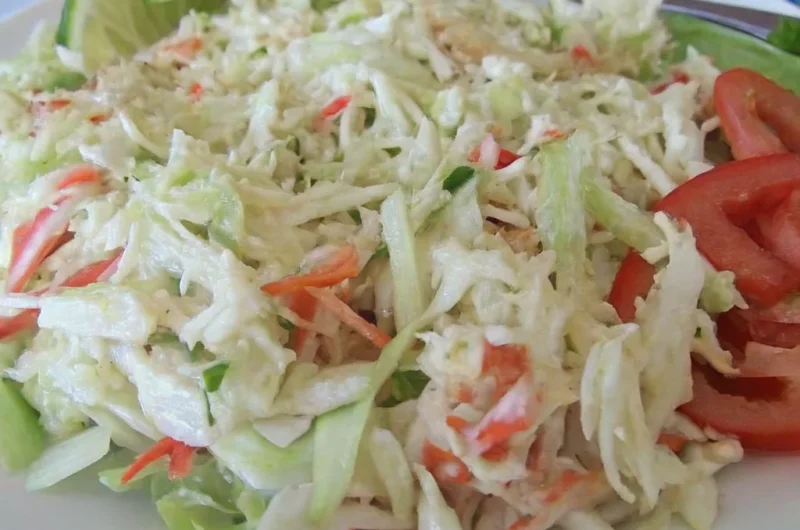 Golden Corral seafood salad with shredded cabbage, imitation crab, carrots, and creamy dressing served with lime and tomato slices.