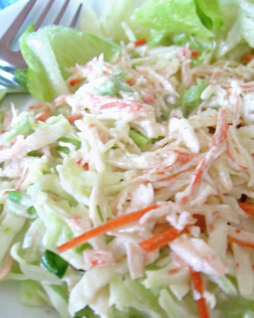 Golden Corral seafood salad with shredded cabbage, imitation crab, carrots, and creamy dressing served with lime and tomato slices.