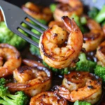 Honey garlic butter shrimp with broccoli in a skillet, garnished with a golden glaze and seared to perfection.
