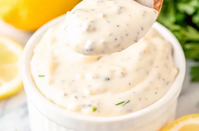 Homemade Red Lobster tartar sauce in white bowl with wooden spoon, showing creamy texture with visible herb and vegetable specks