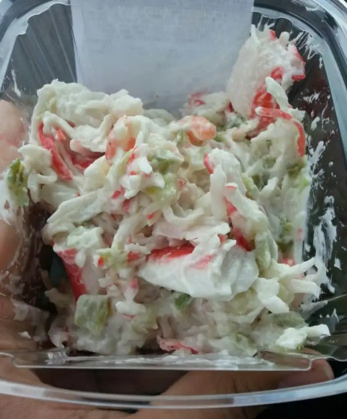The best seafood salad recipe (Publix copycat) with imitation crab, shell pasta, peas, and creamy dressing in a white bowl.