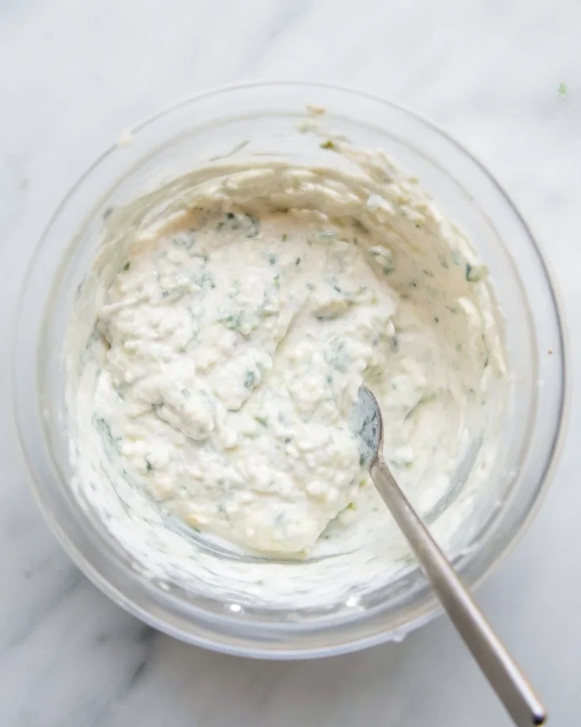 A bowl of creamy smoked salmon dip topped with fresh herbs and flaked salmon pieces.