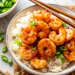 A bowl of honey garlic shrimp served over white rice, garnished with sliced green onions, showcasing an easy shrimp recipe perfect for quick dinners.
