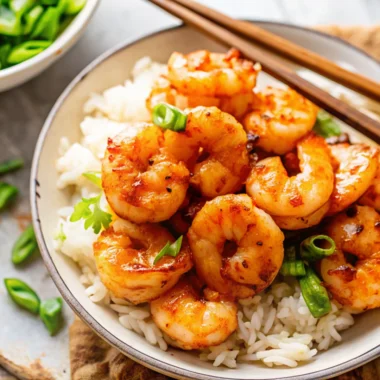 A bowl of honey garlic shrimp served over white rice, garnished with sliced green onions, showcasing an easy shrimp recipe perfect for quick dinners.