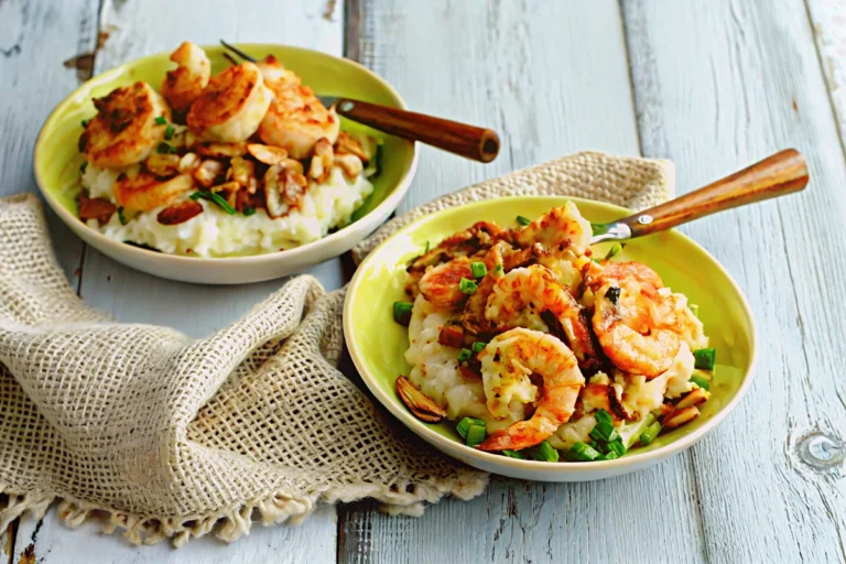 Two bowls of shrimp and grits topped with bacon, mushrooms, and green onions on a rustic wooden table.