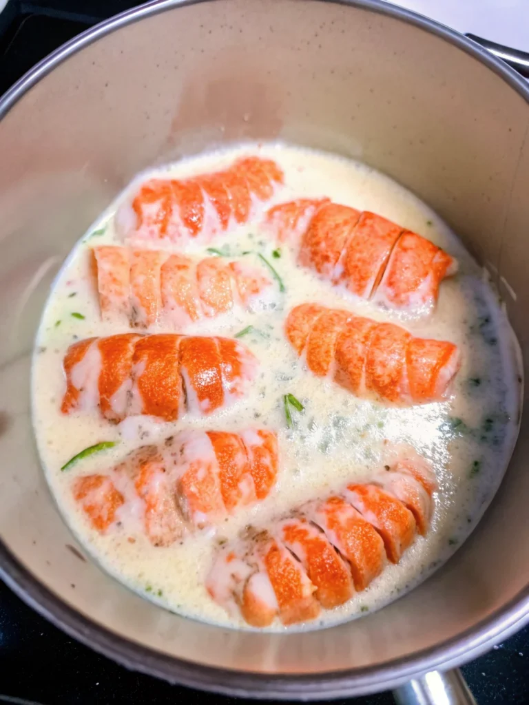 Lobster and risotto served in a bowl, featuring two lobster tails on creamy Arborio rice, topped with butter cubes and garnished with fresh parsley.
